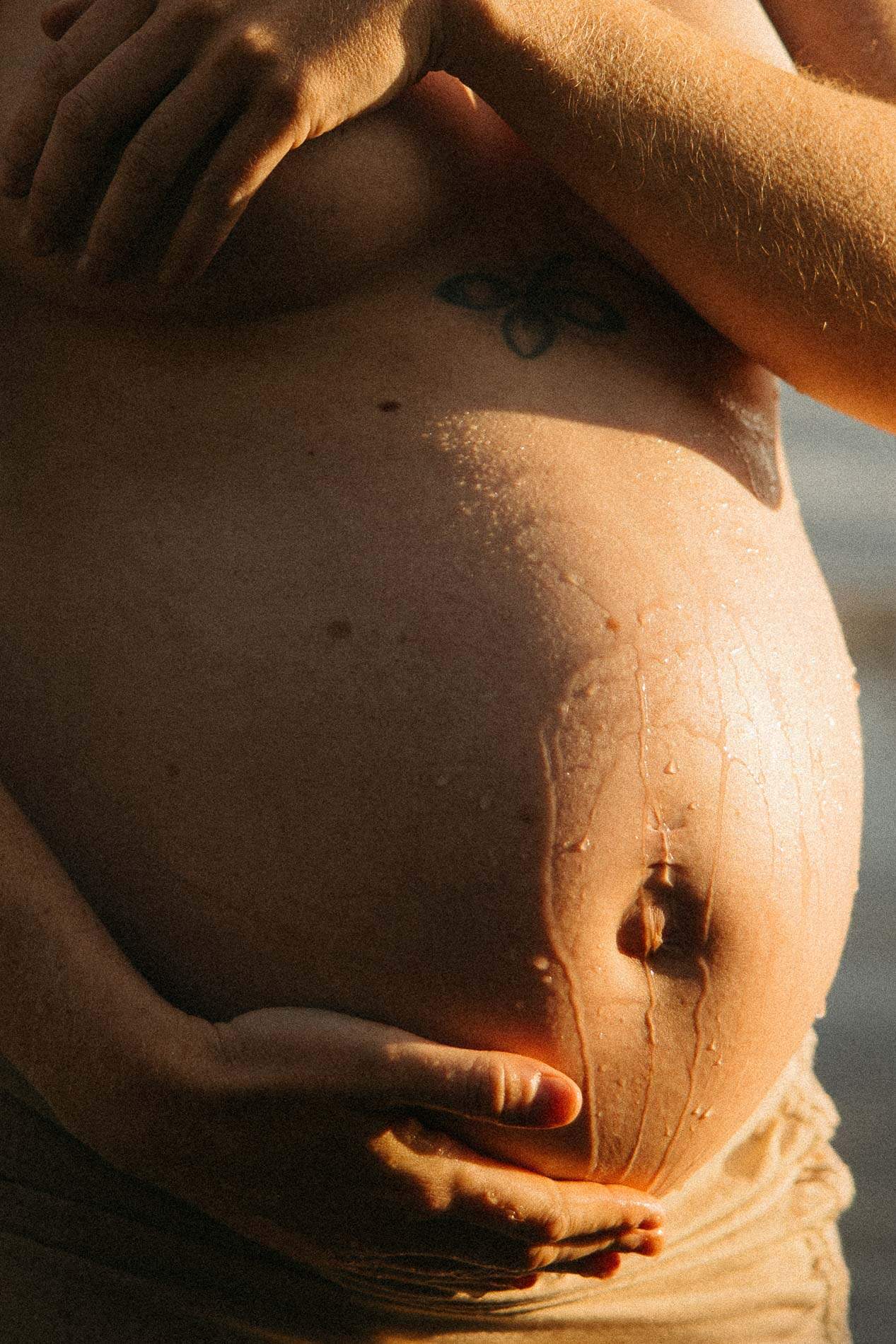 Livmorsfotografi av gravid mage i solnedgang.