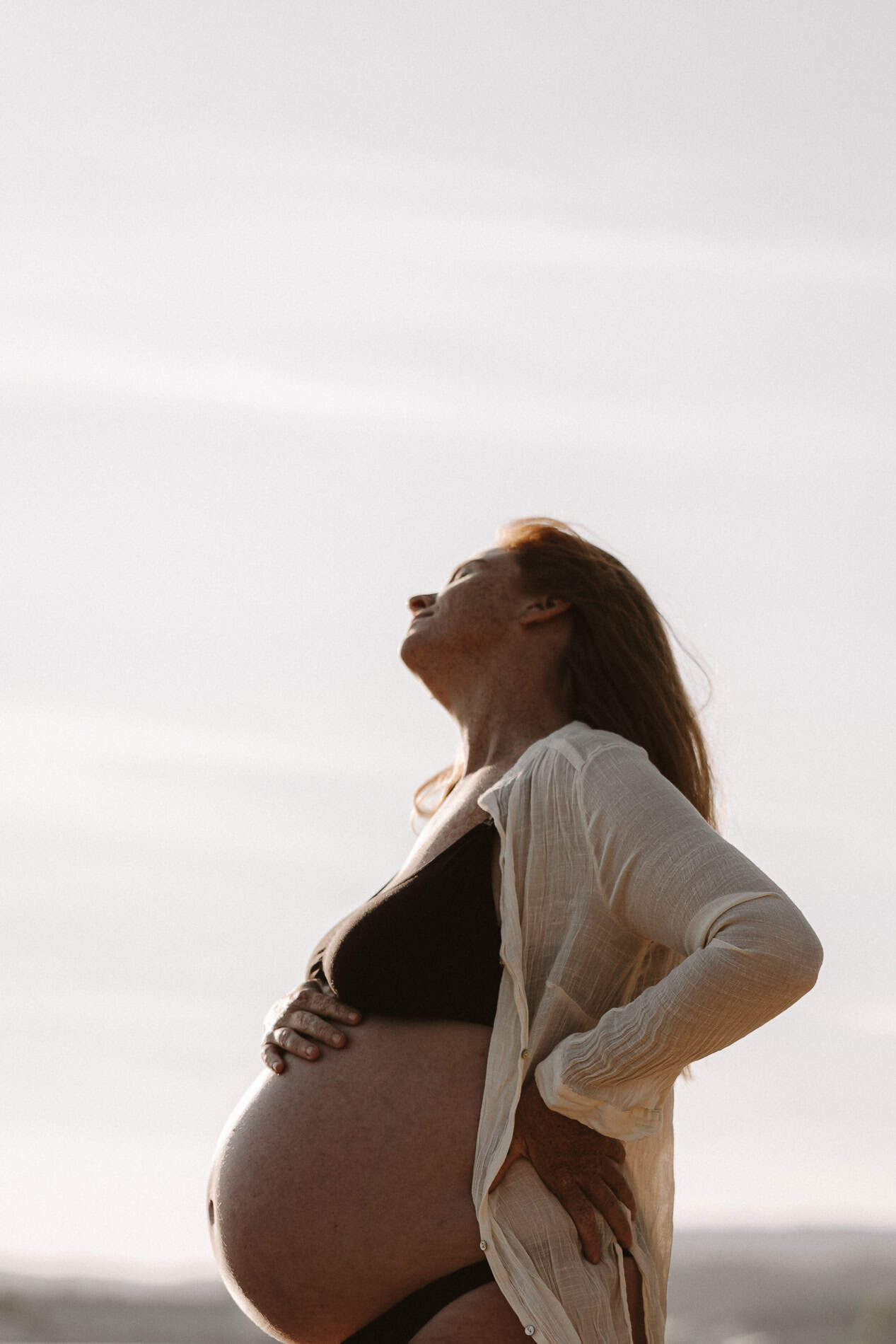 Gravid kvinne som nyter solnedgangen, symbol på livets mirakel og graviditetens skjønnhet.