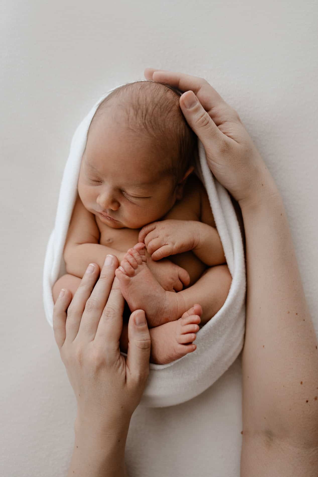 Nyfødt baby som sover, omsluttet av en hvit klut.