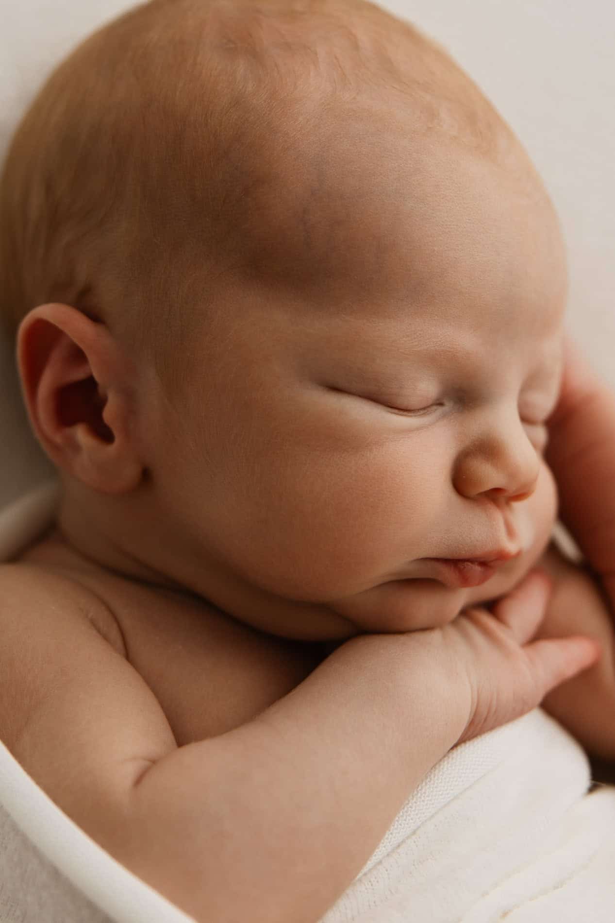 Nydelig baby sover fredelig med lukket øyne og rolig uttrykk.